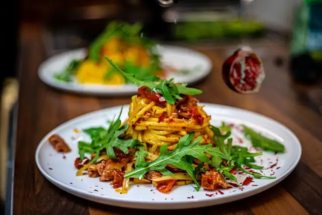 Délicieuses spaghettis à la roquette et grenade avec sauce savoureuse, parfaites pour un dîner italien sain et aromatique.